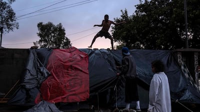 Migrants improvise a tent outside the temporary shelter after heavy rain. AFP