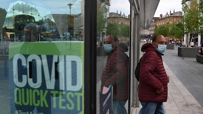 A man wearing a face covering passes a Covid-19 information sign as he exits the Bus Station in Blackburn, north-west England. AFP