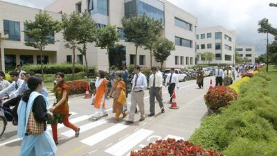 Infosys employees walk in its campus in Bangalore. Many Indians are looking abroad for more work opportunities and better wages. Gautam Singh / AP Photo