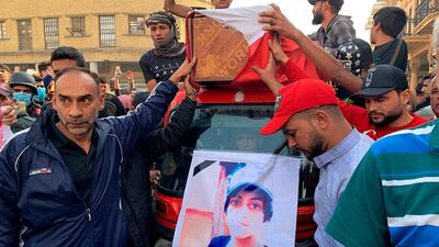 Mourners and protesters escort the flag-draped coffin of Munir Ali, seen in poster, whose family said was killed during anti-government demonstrations, during his funeral in Baghdad. AP Photo