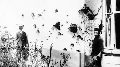 A man stands next to a building damaged by shrapnel from bombs dropped from a Zeppelin in Antwerp, Belgium.