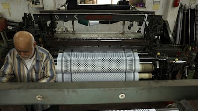 A worker stands over a loom at a textile factory producing the Palestinian Keffiyeh scarf in the occupied West Bank city of Hebron. AFP