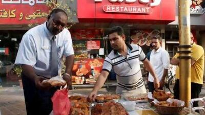 Abdelrahim Osman Gader inspects fried foods displayed outside a restaurant in Deira.