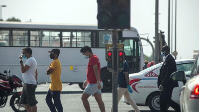 Men wearing face masks at a pedestrian crossing in the Al Quoz industrial area, Dubai. Antonie Robertson/The National