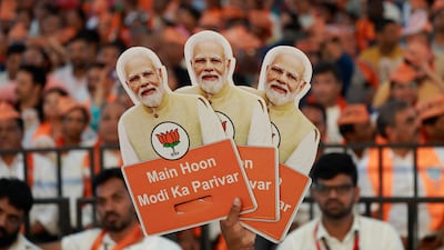 A supporter of India's ruling Bharatiya Janata Party (BJP) holds cutouts of Prime Minister Narendra Modi during an election campaign where Modi speaks, in Bengaluru. Reuters