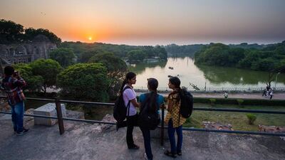 Girls chat as joggers run along the edge of the man-made Hauz Khas lake at Hauz Khas village at duck in New Delhi.