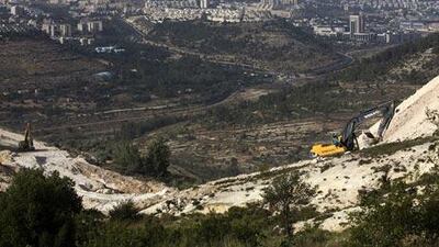 Jerusalem is seen in the background as workers in the West Bank town area of Beit Jala south of Bethlehem build a road funded by USAID , an American government aid agency that has been accused of helping to create "road apartheid" in the West Bank by building dedicated roads for Palestinians that allow Israel to restrict the main highways to Jewish settler traffic.