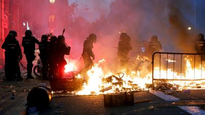 Riot police stand guard next to a burning barricade during Catalonia's general strike in Barcelona, Spain. Reuters