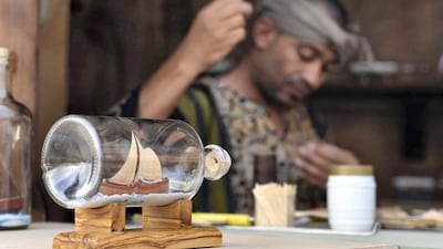 Badr Hashem, Saudi Arabia: An artist is shown with his completed craft of fashioning the almost impossible task of building a tiny ship inside a clear glass bottle in the Okaz Souq near the Saudi city of Ta’if, where a large, diverse group of artists display their crafts.