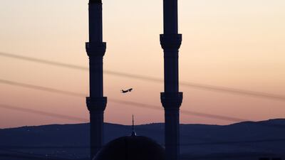 A plane is seen flying beyond mosque minarets as sun rises over the Esenboga Airport in Ankara, Turkey. AFP