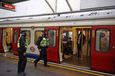 British Transport Police officers check that passengers are wearing face coverings on London underground. AFP