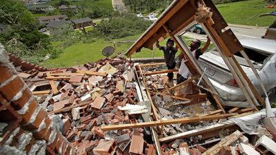 Tavaris McClain, left, and Tyree Thompson clear debris to free McClain's mother's car outside her destroyed home. AP Photo