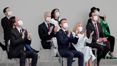 Emmanuel Macron and his wife Brigitte applaud as they watch a military aircraft display in Paris.