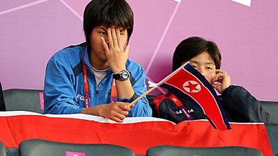 North Korean supporters wait in dismay after their women's football team left the pitch following the flag blunder by Olympic organisers.