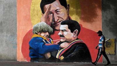 A man walks past a mural in Caracas depicting Venezuelan late President Hugo Chavez saluting and Venezuelan President Nicolas Maduro. AFP
