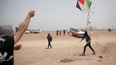 Palestinian protesters fly a kite with a burning rag dangling from its tail during a protest at the Gaza Strip's border with Israel. Khalil Hamra / AP