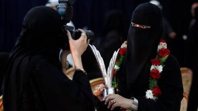 Noora Al Moqitib (R) poses with the trophy as her sister Ayesha Al Moqitib takes her picture during the Mohammed bin Rashid awards for Young Business Leaders in Dubai.