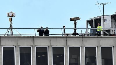 Police officers stand near equipment on the rooftop of a building. AFP