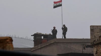 A Syrian national flag flying over a building as regime forces gather in the southern countryside of the northern Kurdish-controlled city of Manbij. AFP