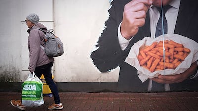 A shopper in the English town of Dudley walks past a mural of former England football manager Sam Allardyce eating chips. Getty Images