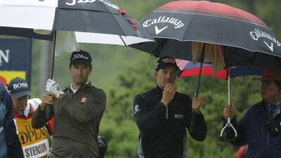 Adam Scott of Australia, left and playing partner Henrik Stenson of Sweden walk off the 12th tee under umbrellas as heavy rain falls during the second round of the British Open Golf Championships at the Royal Troon Golf Club in Troon, Scotland, Friday, July 15, 2016. (AP Photo/Matt Dunham)