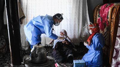TOPSHOT - In this photograph taken on February 15, 2021, Berfo Arsakay (C), 101 years old, prepares to receive a vaccine from doctor Akay Kaya (L) and nurse Yildiz Ayten (R) from the Bahcesaray public hospital vaccination team, at the village of Guneyyamac in eastern Turkey, as part of an expedition to vaccinate residents of 65 years old or above with Sinovac's CoronaVac Covid-19 vaccine. Turkey's population of more than 83 million is spread out across Europe and Asia and covers some seemingly impregnable terrain. The vaccination effort with China's CoronaVac jab kicked off with a bang in mid-January when Turkey innoculated more than a one million people in the first week. But it slowed down considerably when doctors left the big cities and tried to reach mountain places such as Imamli and Ozbeyli -- two ethnically Kurdish hamlets of a few hundred herders and farmers each. / AFP / BULENT KILIC