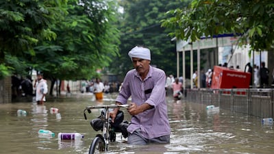 A man pushes his bicycle through a flooded street after heavy rain in Varanasi, India. AFP