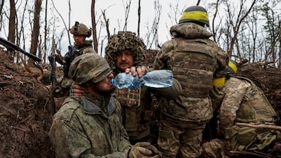 A Ukrainian soldier gives water to a captured Russian army serviceman near Bakhmut, where one of the commanders died. Reuters