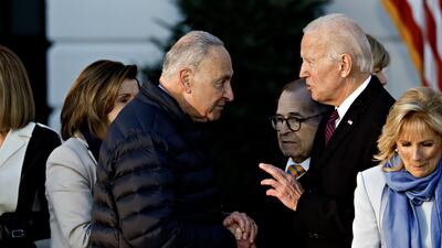 Mr Biden shakes hands with Senate Majority Leader Chuck Schumer after signing the bill. Bloomberg