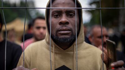 A migrant stands by the fence at the at the newly built refugee camp in the Rudninkai military training ground, near Vilnius, Lithuania. AP