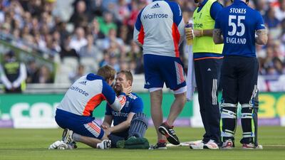 England's captain Eoin Morgan, second left, is treated as he sits on the pitch after being hit on the head off a ball bowled by Australia Mitchell Starc during the deciding one-day international at Old Trafford on Sunday. Jon Super / AP Photo
