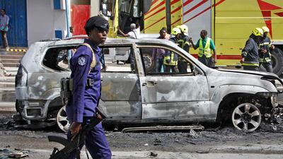 A member of security forces walks past the burned-out vehicle after a bomb planted in it exploded in Mogadishu, Somalia on Tuesday. AP. File photo