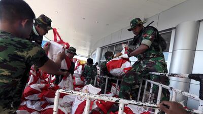 Military personnel unload humanitarian aid and disaster relief supplies at Mutiara Al Jufri Airport in Palu. EPA