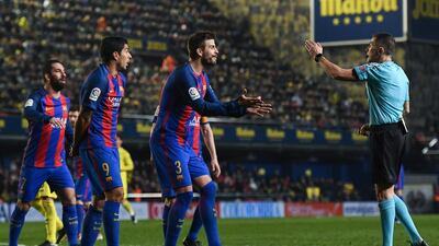 Barcelona’s Luis Suarez, left, and Gerard Pique argue with referee Ignacio Iglesias Villanueva. David Ramos / Getty Images