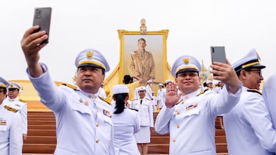 Government officials take selfies in front of a portrait of Thailand’s King Maha Vajiralongkorn during celebrations to mark his 72nd birthday, outside the Grand Palace in Bangkok on July 28, 2024. (Photo by Chanakarn Laosarakham / AFP)