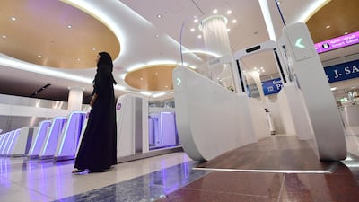 A woman stands next to a "smart tunnel " at Dubai International Airport's terminal 3 in United Arab Emirates on October 10, 2018. - The Smart tunnel using face recognition tecnology, will check the passengers passports as they walk through it. (Photo by GIUSEPPE CACACE / AFP)