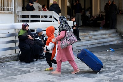 A displaced woman with a child walk outside a school-turned-shelter in Beirut. Reuters