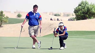 Shloka Desai, 16, lines up a putt during the Pepsi Junior-Am tournament at Els Club yesterday while Jamie Anton, the pro golfer, watches. Desai won the girls' Junior Order of Merit title.