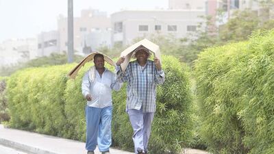 Workers cover their heads with the cardboard to avoid heatstroke during hot weather in Al Satwa area in Dubai in July. Pawan Singh / The National