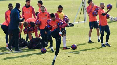 Neymar, centre, kicks a ball to give it to the fans at the end of a training session. Lluis Gene / AFP
