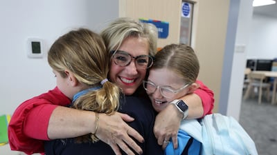 A teacher welcomes children back to class, as schools begin to reopen their doors. Chris Whiteoak / The National