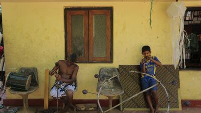 Elandari Devage Tillekaratne, 62, left, the leader of the Walpola Ginikeli Kawaya, or the Walpola Fire Dancers’ Circle, mends a torch used by fire dancers at his courtyard in Walpola, on the outskirts of Colombo. Eranga Jayawardena / AP