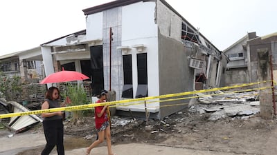 Women walk past a damaged house after a strong earthquake in Davao City, southern Philippines, on Friday. AP Photo