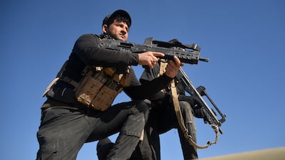 Members of the Iraqi forces and the Hashed Al Shaabi carry their firearms as they stand on an infanty-fighting vehicle near the Iraqi-Syrian border, about 80km west of the border town of al-Qaim, on December 9, 2017.