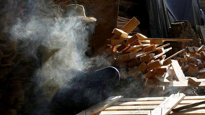 A Thai carpenter, at end of the work day, pauses to smoke a cigarette. Barbara Walton / EPA