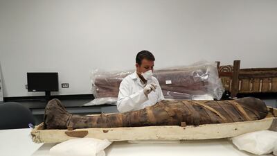 An Egyptian archaeologist check the mummy during restoration work on the coffin of King Tutankhamun at the conservation center in the Grand Egyptian Museum. AFP
