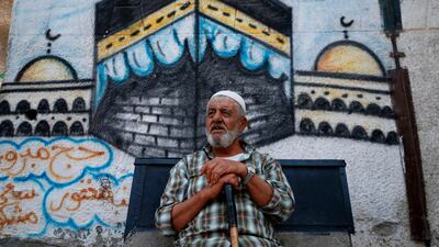 An elderly Palestinian man sits in front of a mural depicting the Kaaba, Islam's holiest shrine, in Gaza City. AFP