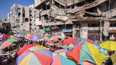 Vendors' umbrellas shade their stalls in front of destroyed buildings in Gaza city. AFP