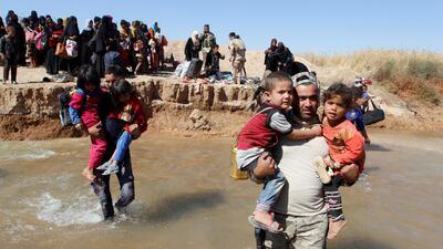A member of the Kurdish Peshmerga forces (right) helps civilians who fled their homes in Hawija as they arrive to be transported to camps for displaced people, in an area south-west of Kirkuk on October 4, 2017. Ako Rasheed / Reuters