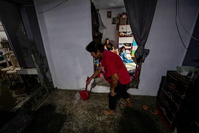 Maria Tamayo scoops water with a plastic dustpan in her home. AFP
